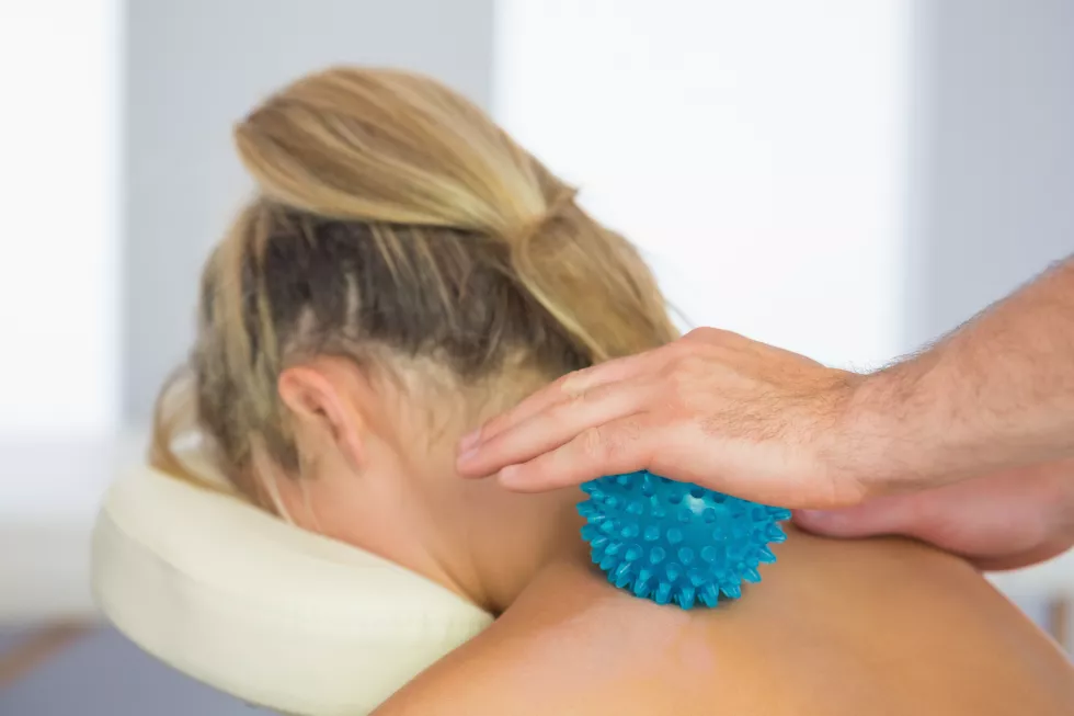 physiotherapist-massaging-female-patient-with-blue-massage-ball